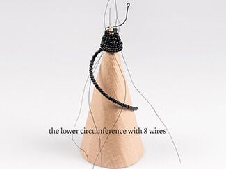 Cardboard cone with beaded wire spiraling around the top showing the final wire configuration